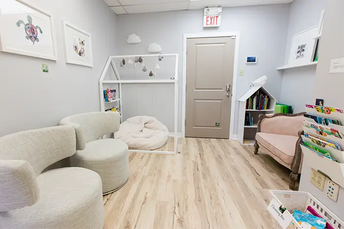 A waiting room area with chairs for parents and child-sized seating, books, and toys for kids.