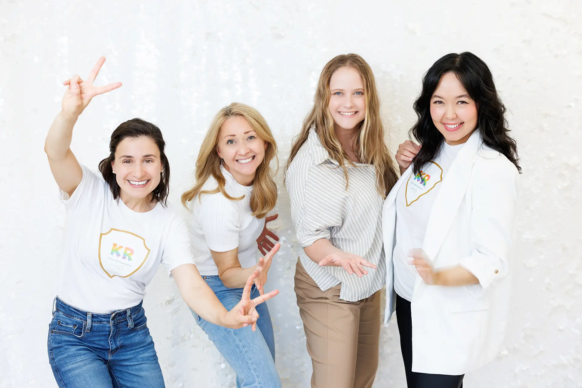 Four women smile and gesture with their hands as they stand side by side.